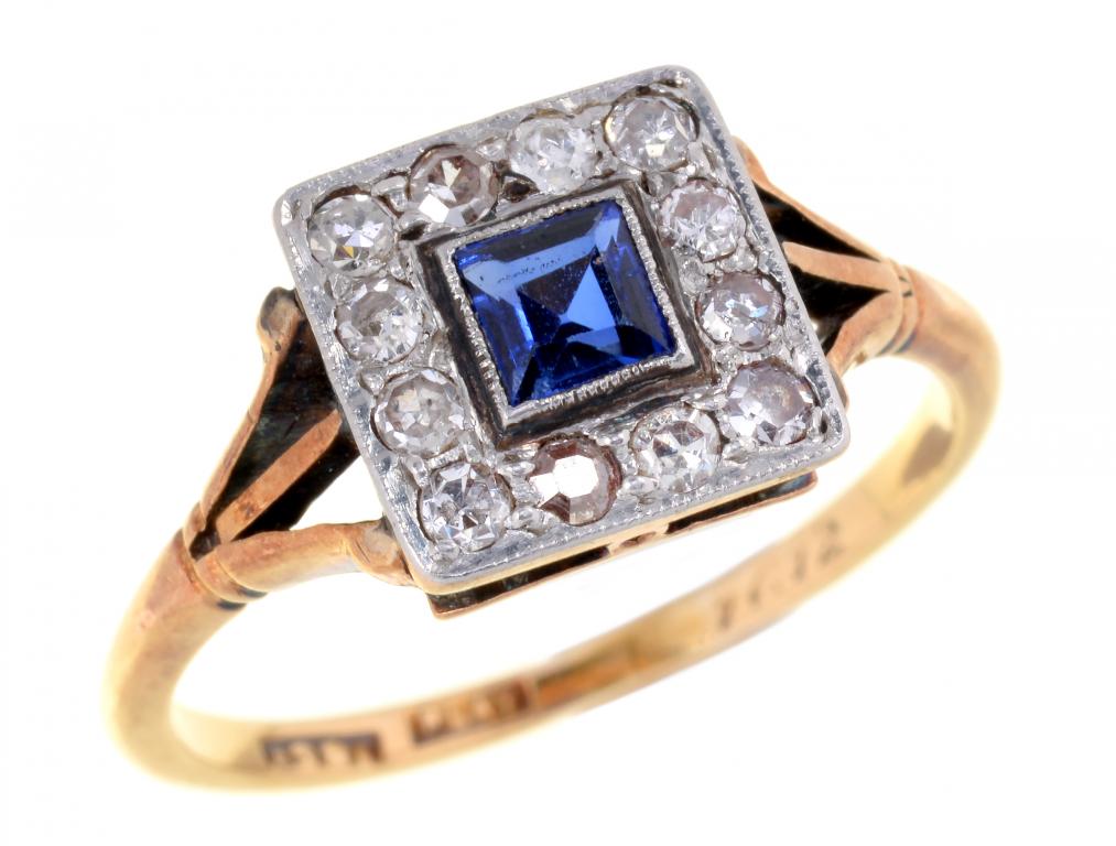 A SAPPHIRE AND DIAMOND CLUSTER RING with central step cut sapphire, gold hoop, marked 18 CT PLAT,