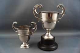 Two silver small campagna shaped trophy cups, each with two flying scroll handles,