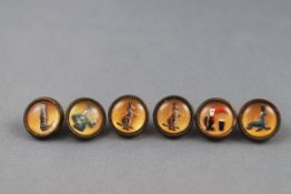 A set of six Guinness waistcoat buttons, each depicting an advertising motif,