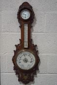 A late Victorian oak aneroid clock barometer with presentation plaque, carved with foliage,