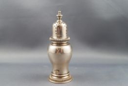 A silver inverted baluster pepper pot with nulled borders the pierced cover with a fluted finial,
