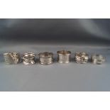 Six silver napkin rings, various designs, dates and makers, 113g gross.