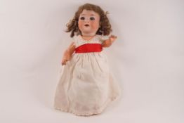 A 20th century German bisque headed doll with rolling blue eyes, open mouth showing teeth,