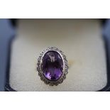 A modern 9ct white gold, amethyst and diamond oval cluster ring,