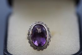A modern 9ct white gold, amethyst and diamond oval cluster ring,