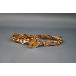 An early 20th century rose gold fancy three-bar gate link bracelet on a foliate engraved padlock