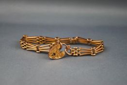 An early 20th century rose gold fancy three-bar gate link bracelet on a foliate engraved padlock