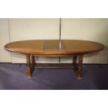 A 20th century oak extending dining table of oval shape, on turned legs with curved H-stretcher,