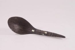 A Maori wooden spoon, the handle carved with a Tiki face inset with paua shell,