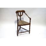 An Arts and Crafts elm corner chair with turned supports and rush seat,