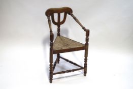 An Arts and Crafts elm corner chair with turned supports and rush seat,
