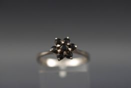 A very dark blue/black sapphire seven stone cluster ring, stamped '925', size R.
