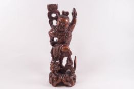 A Chinese carved hardwood figure, of a smiling man standing triumphantly on a mythical creature,