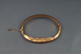 An early 20th centuy 9ct rose gold hollow knife-edge hinged bangle, (badly damaged),