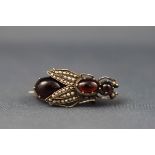 A Continental white metal, garnet cabochon and seed pearl brooch in the form of a winged insect,