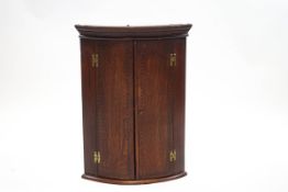 A 19th century oak and inlaid hanging corner cupboard with two shelves,