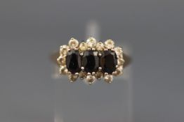 A 9ct gold, sapphire and cubic zirconia triple-cluster ring, the London hallmarks obscured, size R+,