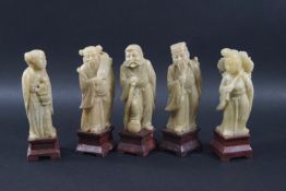A set of five Chinese soapstone figures on wooden stands,