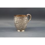 A Chinese export silver small mug with a scroll handle and profusely embossed with bamboo on a matt