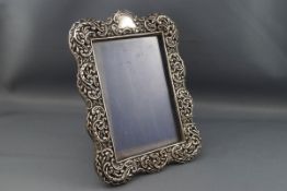 A late Victorian silver mounted photograph frame embossed with scrolls, leaves,