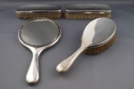 A silver mounted composite four piece dressing table set, comprising; a round hand mirror,