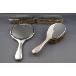 A silver mounted composite four piece dressing table set, comprising; a round hand mirror,