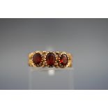 A hallmarked 9ct gold three stone ring set with three oval cut almandine garnets.