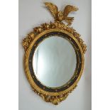 A Regency style round wall mirror in parcel gilt frame with eagle crest,