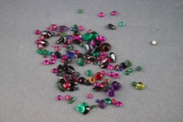A collection of loose gemstones to include garnet, emeralds, rubies, amethyst and sapphire.