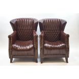 A pair of brown leather armchairs with brass studding and stitched detail,