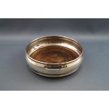 A silver coaster, of plain bulbous form engraved "D", on a turned mahogany base, 13cm diameter,