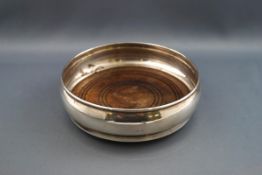 A silver coaster, of plain bulbous form engraved "D", on a turned mahogany base, 13cm diameter,