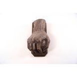 A carved door knocker in the form a hand holding a stone,
