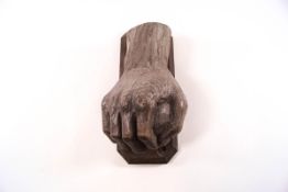 A carved door knocker in the form a hand holding a stone,