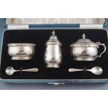 A silver three piece cruet, the salt and mustard with blue glass liners, in original box,