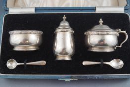 A silver three piece cruet, the salt and mustard with blue glass liners, in original box,