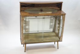 A 1950's display cabinet, with sunburst design above sliding glass doors, enclosing a mirror back,
