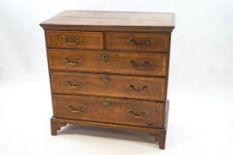 A George III oak and mahogany cross banded chest of two short and three long drawers with brass