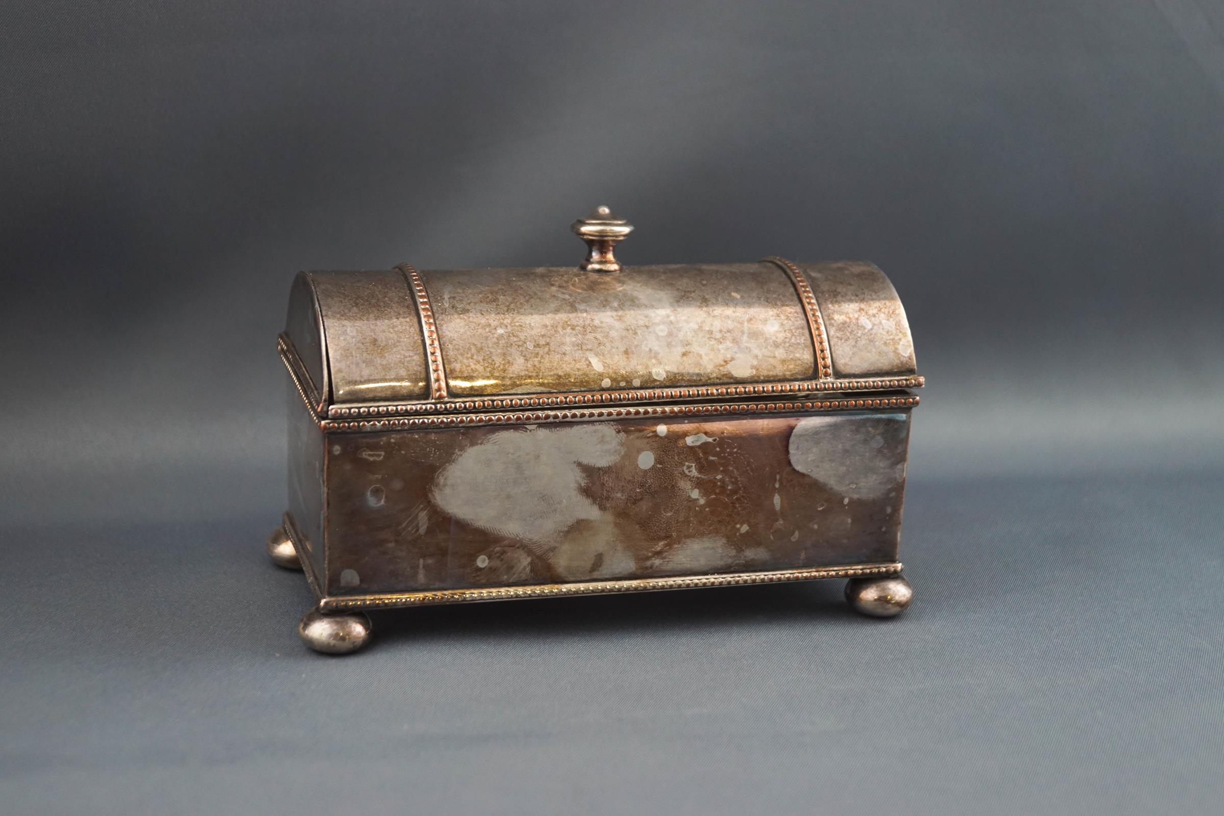 A silver plated inkwell, of domed casket form on four ball feet,