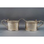A pair of oval silver mustard pots, each with shell thumb piece and double scroll handles,