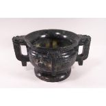 A Chinese carved green hardstone two handled cup of archaic form and decoration,