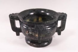 A Chinese carved green hardstone two handled cup of archaic form and decoration,