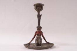 An Art Nouveau painted metal candlestick modelled as a kneeling lady on a lily pad,