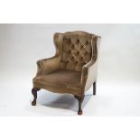 A George III style wing back armchair on carved cabriole legs with claw and ball feet,