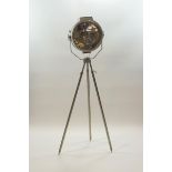 A large industrial metal lamp on tripod base with adjustable swivel head,