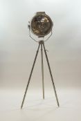 A large industrial metal lamp on tripod base with adjustable swivel head,