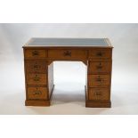 An Edwardian oak pedestal desk with three drawers below a green leather inset writing surface,