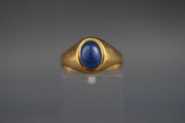 A yellow metal single stone cabochon ring set with blue glass. Stamped 18ct. 3.