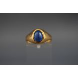A yellow metal single stone cabochon ring set with blue glass. Stamped 18ct. 3.