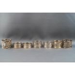 Two pairs of pierced silver napkin rings, together with three other napkin rings,